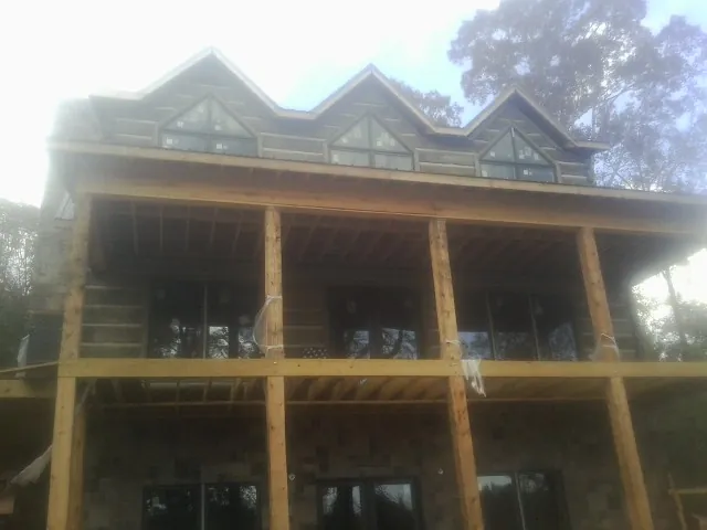 Dormers and porch framing on a large log home under construction — Roof Coating work by our crew in Newcastle